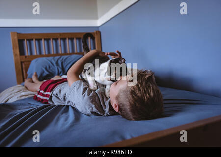 Junge spielt mit cat im Schlafzimmer Stockfoto