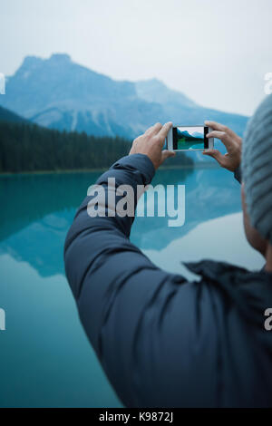 Rückansicht des Menschen ein Bild mit seinem Handy in der Landschaft Stockfoto