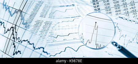 Aktienkurse, Charts und eine Lupe mit Aktienpreis im Detail. Stockfoto