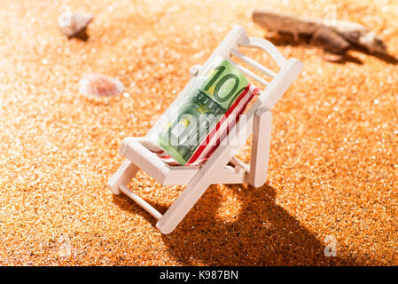 Ein gerolltes 100-Euro-Banknote auf einer Liege in einem Beach Szene Stockfoto