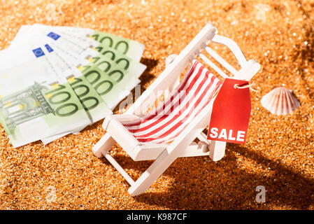 Liegestuhl am Strand, Rabatt Label mit dem Wort Verkauf und Banknoten Stockfoto