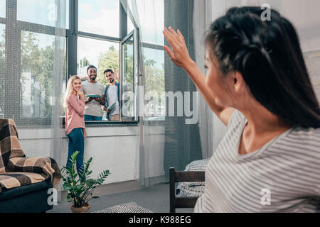 Junge Frau winkte an Freunde Stockfoto