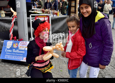 Kinder- Entertainer clown, der Ballon Tiere für die Kinder hier mit einer Familie in Bristol Ereignis Stockfoto