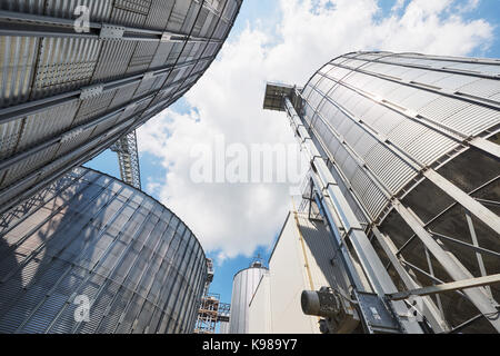 Landwirtschaftliche Silos. Gebäude Exterieur. Lagerung und Trocknung von Getreide, Weizen, Mais, Soja, Sonnenblume gegen den blauen Himmel mit weißen Wolken Stockfoto