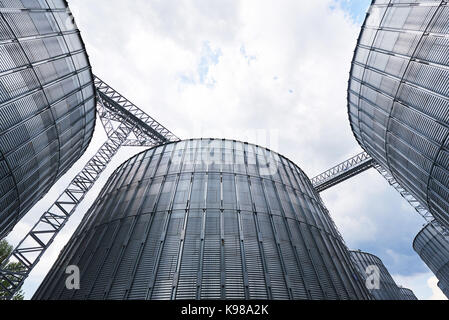 Landwirtschaftliche Silos. Gebäude Exterieur. Lagerung und Trocknung von Getreide, Weizen, Mais, Soja, Sonnenblume gegen den blauen Himmel mit weißen Wolken Stockfoto