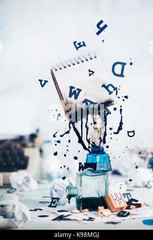 Notebook mit leeren Seiten und verschüttete Tinte fliegen oben Tintenfässer mit vereinzelten schwarzen Buchstaben auf einem hellen Hintergrund. Immer noch leben mit dem Schriftsteller Arbeitsplatz. Stockfoto