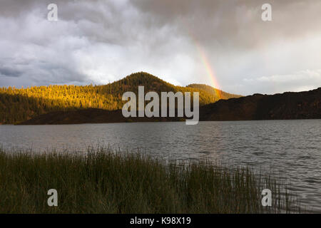 Ein Regenbogen Bogen erhebt sich über das Lavafeld am südlichen Ufer des Butte Lake in den Lassen Volcanic National Park. Stockfoto