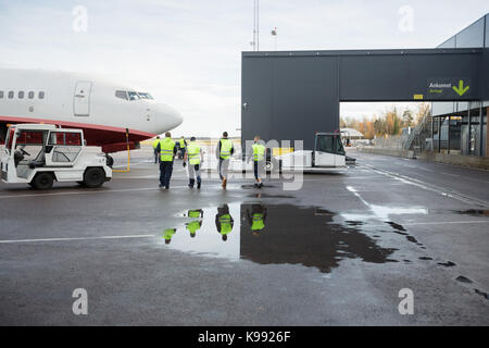 Arbeitnehmer auf dem Weg zum Flugzeug Auf nasser Piste Stockfoto