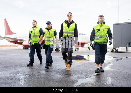 Die volle Länge der Arbeitnehmer gehen auf nassen Landebahn Stockfoto