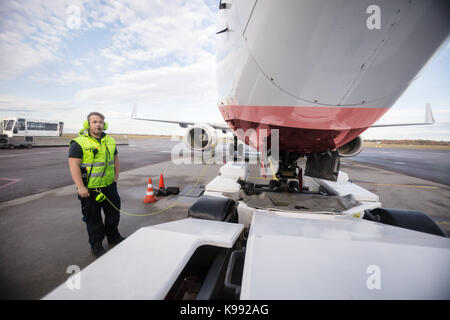 Arbeitnehmer stehen mit dem Flugzeug mit Kommunikation Kabel auf Start- und Landebahn Stockfoto