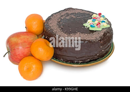 Eine große Schokolade Kuchen mit Dekoration in Form von einem Weihnachtsbaum auf einem keramischen Teller und Obst. Auf einem weißen Hintergrund dargestellt. Stockfoto
