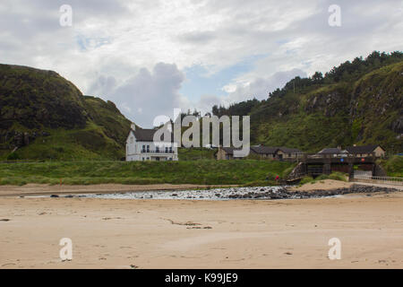 Ein gepflegtes Einfamilienhaus und Garten mit einem Fluss unter einer kleinen Brücke. Am Strand in Downhill in der Grafschaft Londonderry, N Stockfoto