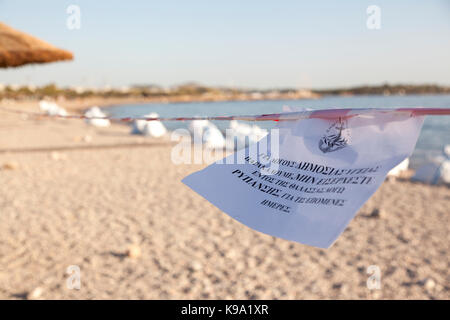 Ein Papier unterschreiben in der Griechischen, die darauf hinweist, dass das Schwimmen ist in den Strand von Glyfada (Saronischer Golf, Athen, Griechenland) untersagt, die durch die Ölpest Umweltverschmutzung. Stockfoto