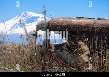 Aufgegeben und rostigen alten sowjetischen Russischen Bus mitten im Schilf und Landwirtschaft Felder mit Schnee - malerische Berg Ararat und dem klaren, blauen Himmel begrenzt auf Stockfoto