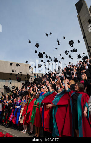 Hochschulbildung im Vereinigten Königreich: Aberystwyth Studenten tragen traditionelle akademische Kleider, ihren Erfolg feiern, indem sie ihre Mörser Bretter werfen in der Luft auf ihre Graduation Day, Juli 2017 Stockfoto