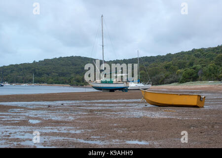 Als die Flut erlischt, Boote sind hoch und trocken auf dem Sand links. Stockfoto