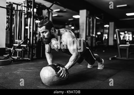 Bemuskelt junger Mann Sport Verschleiß und tun Ganzkörperstütz während des Trainings auf dem Boden im Loft Innenraum Stockfoto