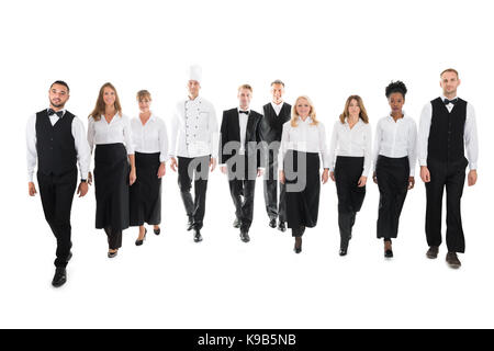 Volle Länge Portrait von zuversichtlich, das Personal im Restaurant wandern in der Zeile vor weißem Hintergrund Stockfoto