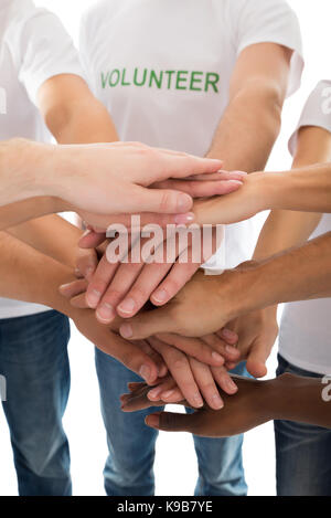 Mittelteil der multiethnischen Freiwillige piling Hände vor weißem Hintergrund Stockfoto