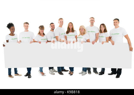 Volle Länge Portrait von zuversichtlich freiwillige Holding leere Plakatwand vor weißem Hintergrund Stockfoto