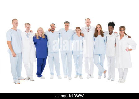 Volle Länge Portrait von zuversichtlich medizinisches Team stehend mit Arme um gegen den weißen Hintergrund Stockfoto
