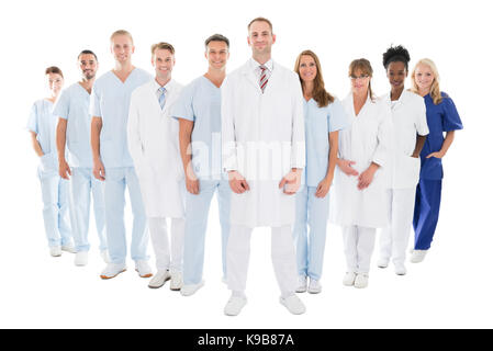 Volle Länge Portrait von zuversichtlich Arzt mit seinem Team gegen den weißen Hintergrund Stockfoto