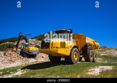 VOGEL BERG, Slowenien - 30. AUGUST 2017: Bau von Maschinen für das Zerkleinern von Stein, Volvo Bulldozer und großen Lkw kipper Arbeiten am Berg slop Stockfoto