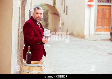 Reifen glücklicher Mann mit einem Glas Rotwein im Freien in alten italienischen Dorf Stockfoto