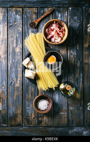 Zutaten für traditionelle italienische Pasta alla Carbonara. Ungekochte Spaghetti, bauchspeck Speck, Parmesan, Eigelb, Salz, Pfeffer in Olivenholz bo Stockfoto