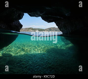 Über und unter dem Meer in eine Höhle an der Küste mit der mediterranen Dorfes El Port de la Selva und Kieselsteinen Unterwasser, Spanien, Costa Brava Stockfoto