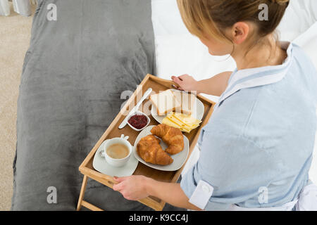Close-up weiblichen Maid mit Frühstück Tablett im Schlafzimmer Stockfoto