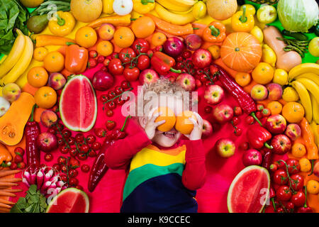 Jungen mit Auswahl an Obst und Gemüse. Bunte Regenbogen von rohem Obst und Gemüse. Kind, gesunden Snack zu essen. Vegetarische Ernährung fo Stockfoto