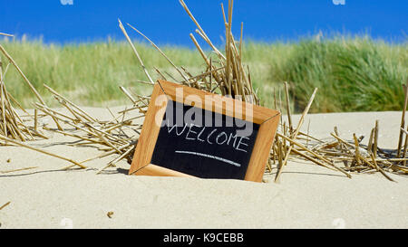 Willkommen auf einer Schiefertafel am Strand im Sommer geschrieben Stockfoto