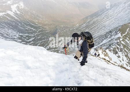 Wanderer mit Eispickel Klettern Swirral Kante im Winter, Helvellyn, Lake District, Cumbria, Großbritannien Stockfoto