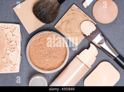 Make-up-Produkte und Zubehör, um sogar aus Hautton und Teint auf Grau texturierte Oberfläche Stockfoto