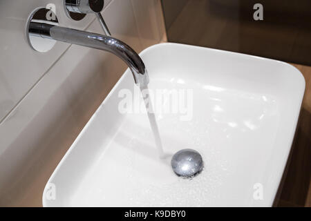 In der Nähe von Waschbecken und Wasserhahn auf Holzregal in Weiß Bad Stockfoto