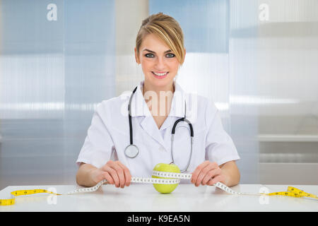 Gerne weibliche Ernährungsberater Messen Green Apple mit Maßband Stockfoto