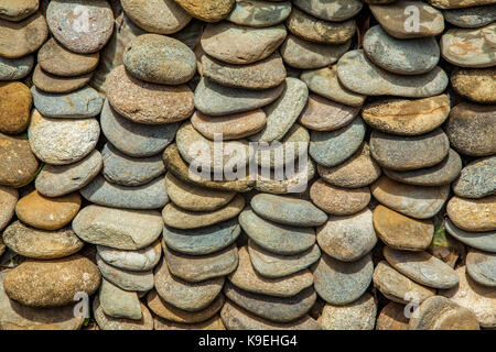 Abstraktes Muster aus kleinen, runden, bunten Steinen in Zeilen als Mulch verwendet gestapelt. Stockfoto