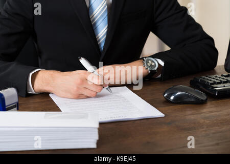 Nahaufnahme der Geschäftsmann Unterzeichnung mit Pen Vertrag Papier am Schreibtisch Stockfoto