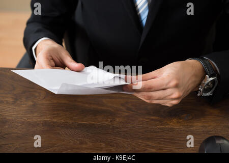 Nahaufnahme der Geschäftsmann mit Umschlägen am Schreibtisch am Arbeitsplatz Stockfoto