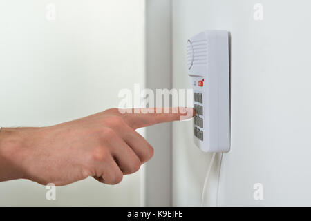 Nahaufnahme der Person Hand Druck auf den Knopf an der Tür Sicherheit System Stockfoto