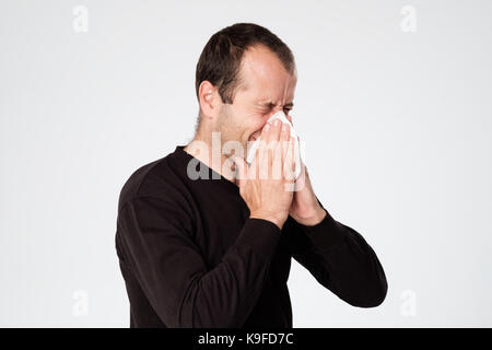 Reifer Mann ist krank von Erkältungen oder Lungenentzündung, Niesen in Serviette. Leiden von der Grippe Virus. Stockfoto