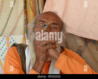 Alte indisch-hinduistischen Sadhu mit zurücktretenhaarstrich, rauchen Haschisch (Marihuana, Ganja, bhang, weed) in einem Chillum pipe, halten Sie das Rohr mit beiden Händen Stockfoto