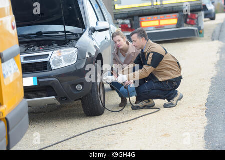Männliche Mechaniker Aufpumpen eines PKW-Reifen in der Nähe von seinen weiblichen Client Stockfoto