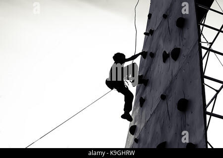 Free climber Kind junge Praktizierende auf künstliche Felsbrocken in der Turnhalle, Bouldern. Stockfoto