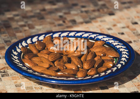 Gebratene Mandeln in weißer Teller am Tisch Hintergrund Stockfoto