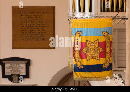 Badewanne und Bezirk Afrika Star Association Flagge. Banner hängen in Saint Michael's ohne Kirche mit dem Gebet des Herrn im Hintergrund Stockfoto