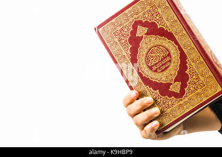 Koran in der Hand, Koran in der Hand - das heilige Buch der Muslime, auf weißem Hintergrund Stockfoto