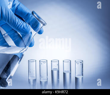 Labor-Becher in der Hand des Analytikers in Kunststoff-Handschuh. Stockfoto