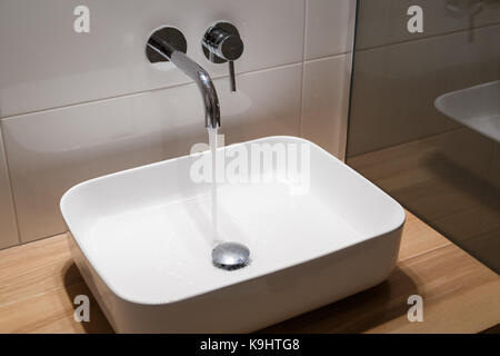 In der Nähe von Waschbecken und Wasserhahn auf Holzregal in Weiß bad Interieur. Stockfoto